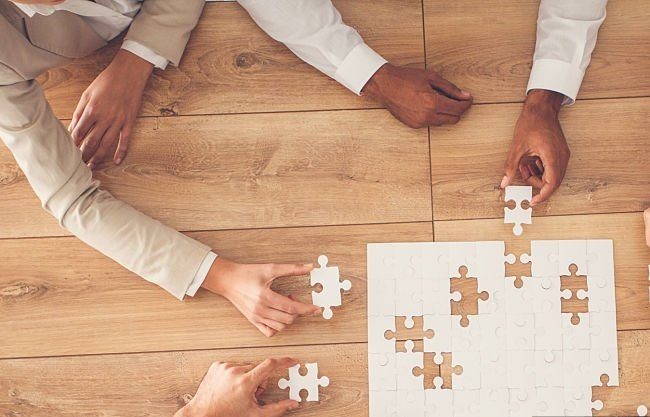 school Business people sitting at office desk, putting puzzle pieces together, finding solution, high angle view.